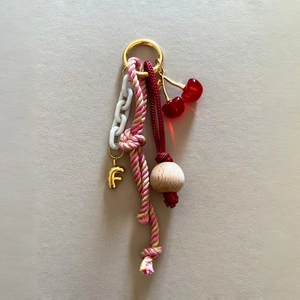 Detail of keychain with colorful woven rope, wooden beads, cherry charm, and letter F pendant