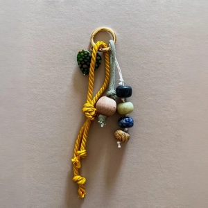 Detail of a handmade yellow woven rope keychain with floral heart and stone beads