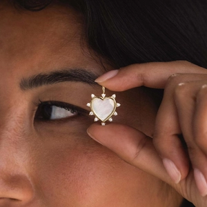 Detalle de un colgante de corazón dorado con nácar y pequeñas circonitas de alta calidad
