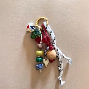 Detail of colorful beads, wooden bead, and woven cords on a golden carabiner bag charm