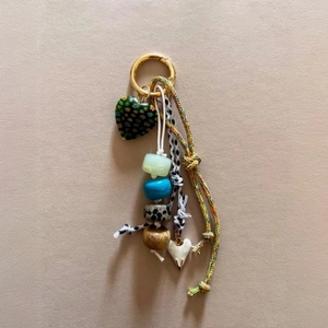 Detail of bohemian bag charm with green heart pendant and colorful braided rope