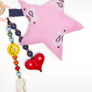 Macro detail of a colorful paisley star bag charm with beads, smiley face and heart pendant