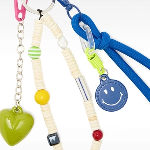 Detail of colorful charm set with green heart, beaded strap, and blue smiley face pendant
