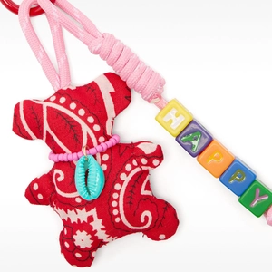 Detailed macro view of a red paisley teddy bear bag charm with colorful HAPPY letter beads