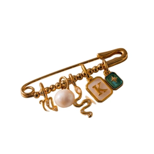 Broche de imperdible dorado con dijes de luna, perla, serpiente y la letra K