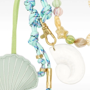 Detail of sea-themed bag charms featuring mint shell leather and resin conch accessories