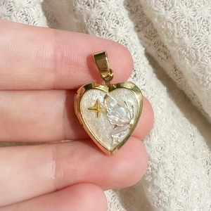 Détail d'un médaillon cœur en or 18K avec aile de papillon et incrustation en nacre