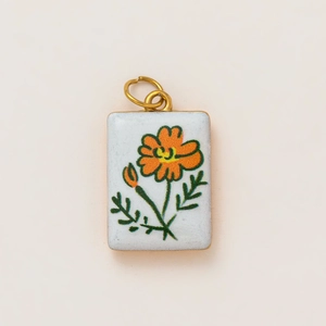 Detail of a rectangular white keychain pendant with orange flower print and gold ring
