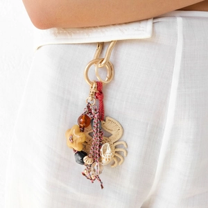Close-up of a handmade woven crab charm with shells and beads on a summer bag accessory