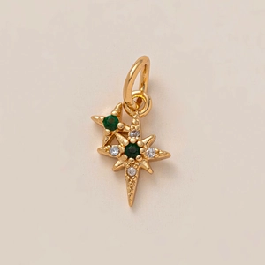 Détail macro du pendentif double étoile en laiton doré avec des pierres vertes