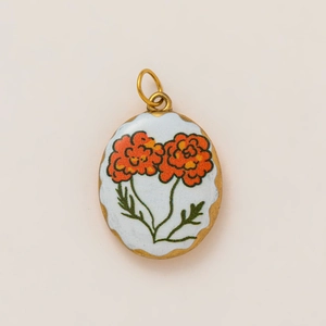 Detailed macro view of vintage oval gold pendant with hand-painted orange floral enamel inlay