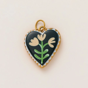 Macro detail of 18K gold-plated heart pendant with floral enamel and wave pattern