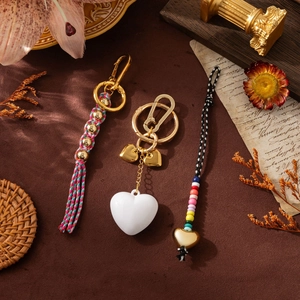 Porte-clés tissés main avec perles colorées, pompons et pendentifs cœur sur décor vintage