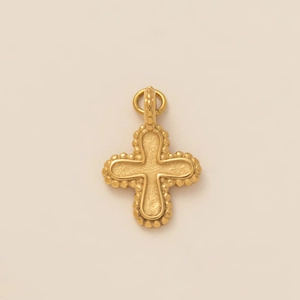 Close-up of golden stainless steel cross pendant with bead edges and matte finish