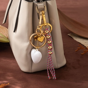 Porte-clés tissé main avec pendentif cœur blanc et pompon coloré sur un sac en cuir