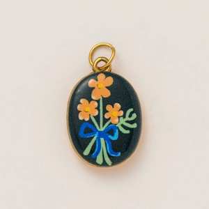 Detailed close-up of oval stainless steel 18K gold pendant with blue floral enamel