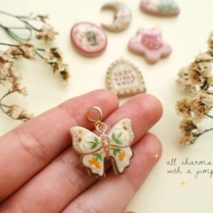 Detail eines handgefertigten Schmetterlingsanhängers mit Blumenmuster und 14K Goldring