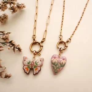 Detail von 14K vergoldeten Halsketten mit handbemalten Schmetterlings- und Herzanhängern