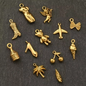 Detailed view of various 18K gold plated charms including heart, bear, and boots on stone