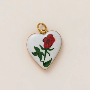 Detailed macro view of heart-shaped white enamel pendant with vintage red rose floral pattern