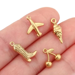 Detailed close-up of 18K gold plated charms including aircraft, ice cream, boot and cherries
