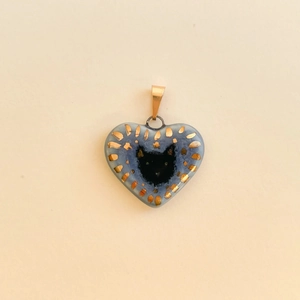 Detail of blue heart pendant with hand-painted black cat motif and gold foil edges