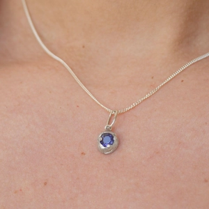 Makroaufnahme einer 18K Goldkette mit einem leuchtend blauen Tansanit-Edelsteinanhänger für Damen