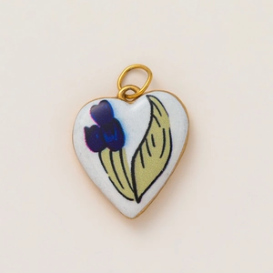 Detailed macro view of heart enamel pendant with blue flower patterns and gold edging