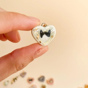 Detail of a handmade heart-shaped pendant featuring a cat motif and 18K gold accents