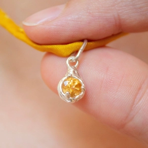 Detail eines 18K Goldanhängers mit facettiertem gelbem Edelstein und Emaille
