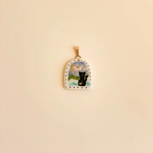 Macro shot of 18K gold-plated arch pendant with hand-painted black cat and moon
