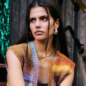 Minimalist gold heart lock necklace and geometric earrings worn with a colorful knit vest