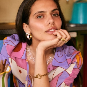 Close-up of golden heart buckle bracelet and pink stone earrings on a female model