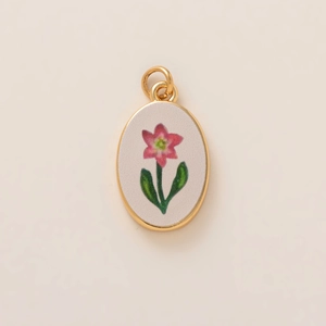 Dettaglio del ciondolo a fiore ovale placcato in oro con petali rosa e foglie verdi