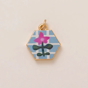 Detailed macro view of a hexagonal pendant with pink floral pattern and gold metal frame
