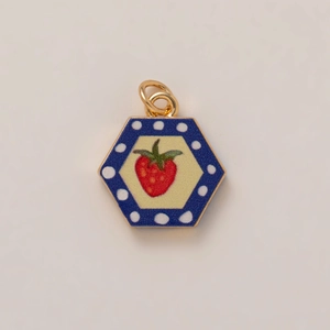 Macro shot of hexagonal strawberry pendant with blue polka dot border and gold metal rings