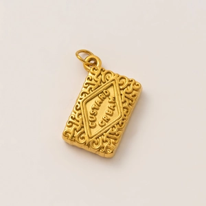 Macro detail of a 18K gold-plated custard cream biscuit pendant with floral engraving