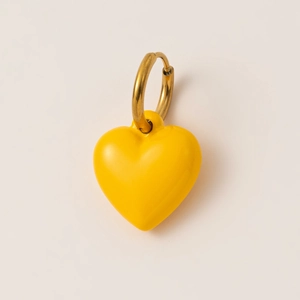 Detalle de un pendiente de aro bañado en oro de 18K con un colgante de corazón amarillo