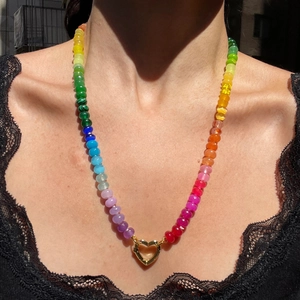 Detail of colorful beaded rainbow necklace with gold heart-shaped pendant on black lace