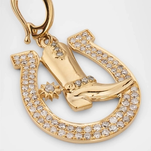 Macro detail of 18k gold cowboy boot and horseshoe pendant with sparkling zircon inlay