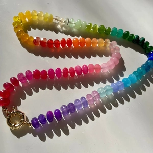 Detailed close-up of rainbow bead necklace with a gold spring clasp on white background