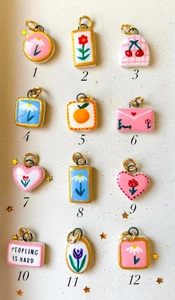 Detailansicht von 12 handbemalten Anhängern mit Blumen- und Fruchtmotiven und Goldrand