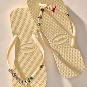 Close-up of cream flip-flops with ocean-themed charms including shells and lobster pendants