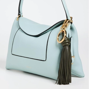 Detail of light blue textured leather handbag with olive green fringe and gold hardware