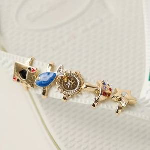 Detail of five distinct alloy shoe charms including Poker Ace on white flip-flop straps