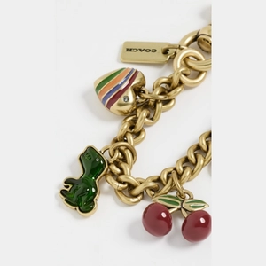Macro detail of dinosaur, cherry, and heart enamel charms on a vintage gold bag chain