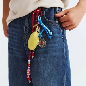 Fashionable bag pendant with yellow leather pouch and heart tennis racket on jeans