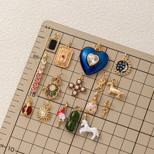 Assortiment de breloques dorées avec motifs cœur, licorne et étoiles sur grille