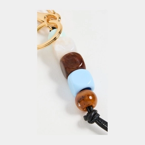 Detail of colorful resin beads and leather cord on a gold metal keychain accessory