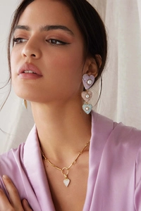 Close-up of heart-shaped earring and necklace set with zircons and pearls on a model